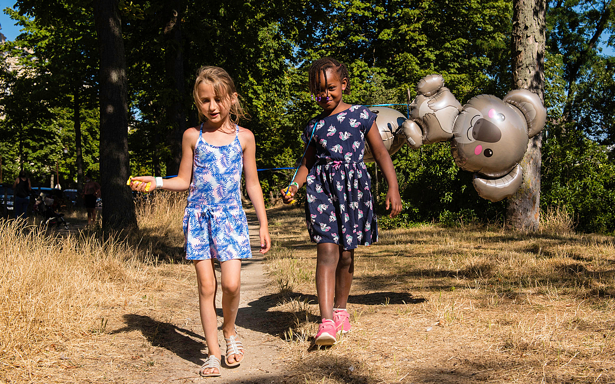 Deux petits filles se baladent avec des ballons gonflés en forme de koalas.