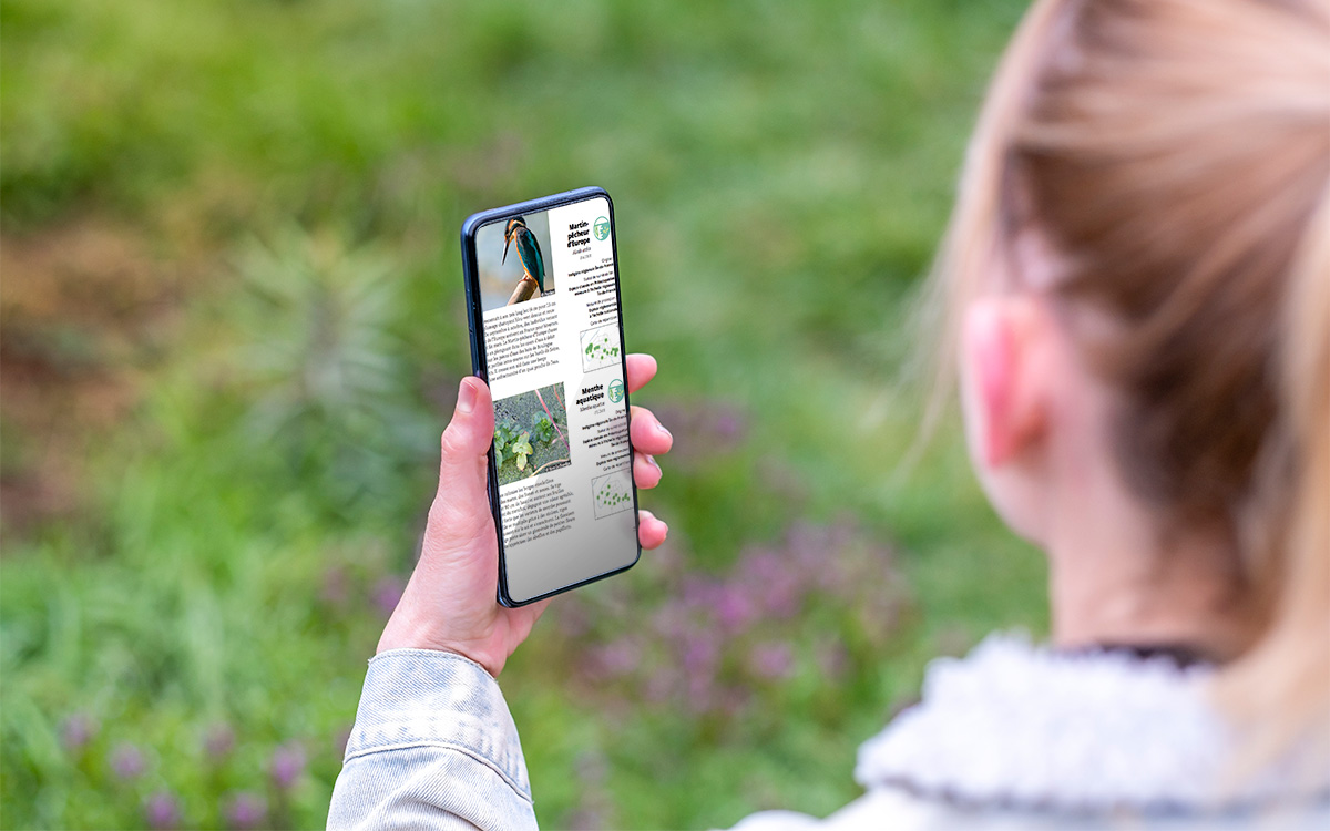 Une jeune fille consulte l'Atlas de la Nature de Paris sur son smartphone