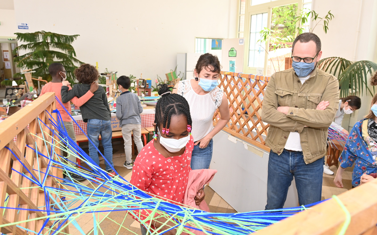 Journées des Arts Plastiques 2021 "Tissage" Une enfant observée en plein tissage de fil de laine par son professeur d'Arts Plastiques et Emmanuel Coblence (Conseiller de Paris délégué à l’éducation, aux nouveaux apprentissages et aux relations avec la Caisse des écoles). Lieu du reportage : Centre Paris Lecture, Corvisart, 13e