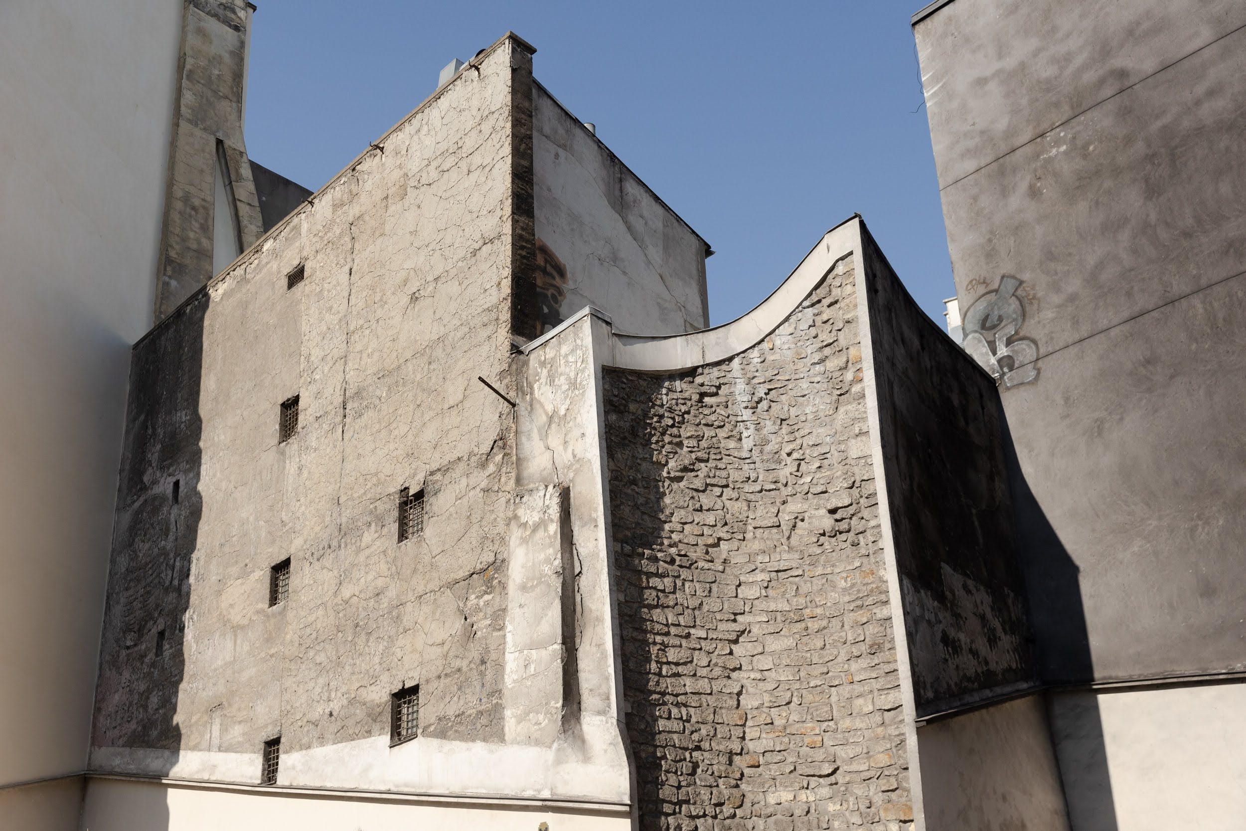 Ancienne tour médiévale cernée par des immeubles plus modernes.